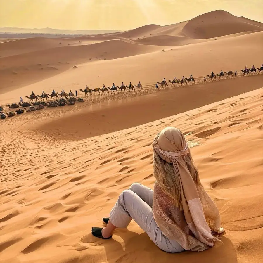 Vista aérea de dunas con caravana de camellos