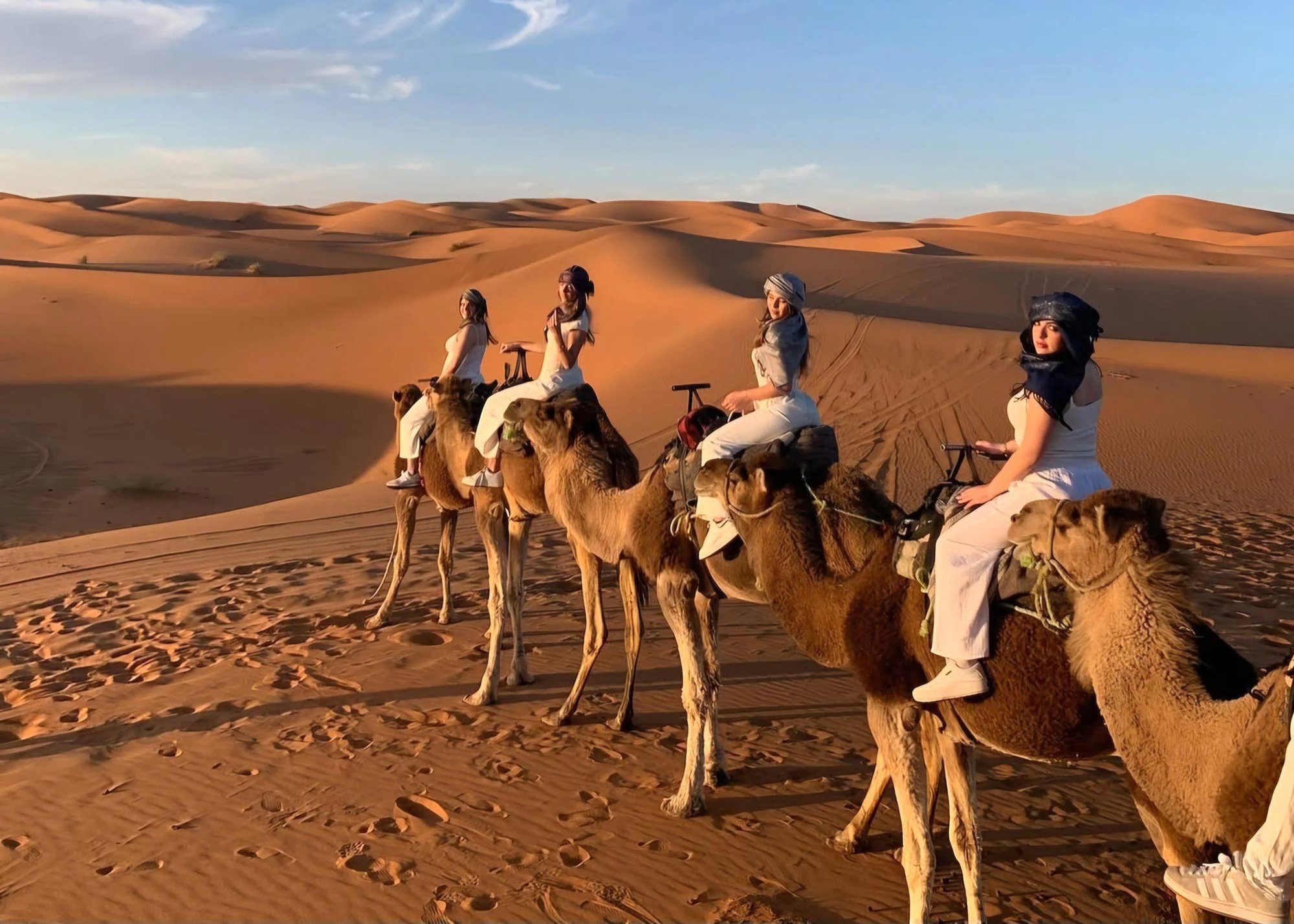 Grupo de viajeras en camello por las dunas de Merzouga al atardecer